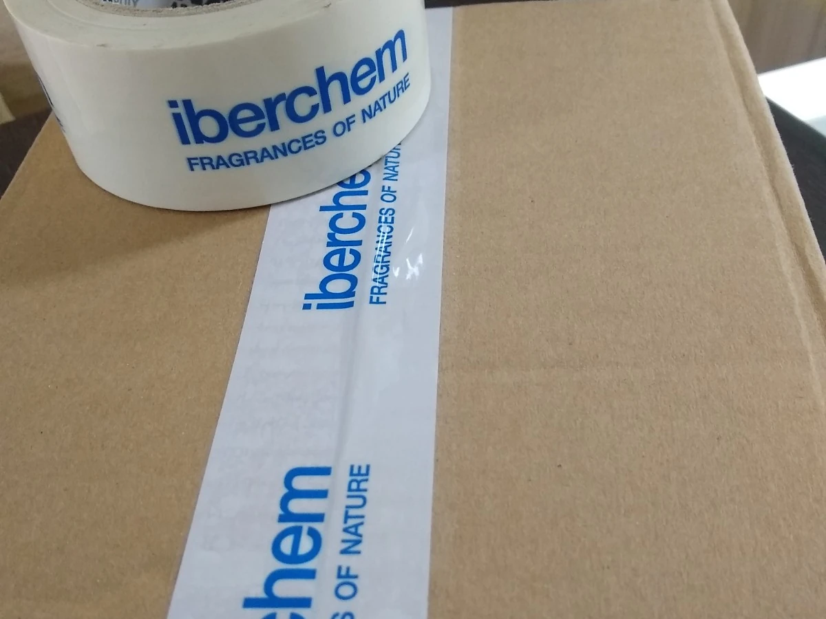 Cinta de precinto con la marca del cliente impresa, aplicada sobre una caja de cartón cerrada, junto al rollo