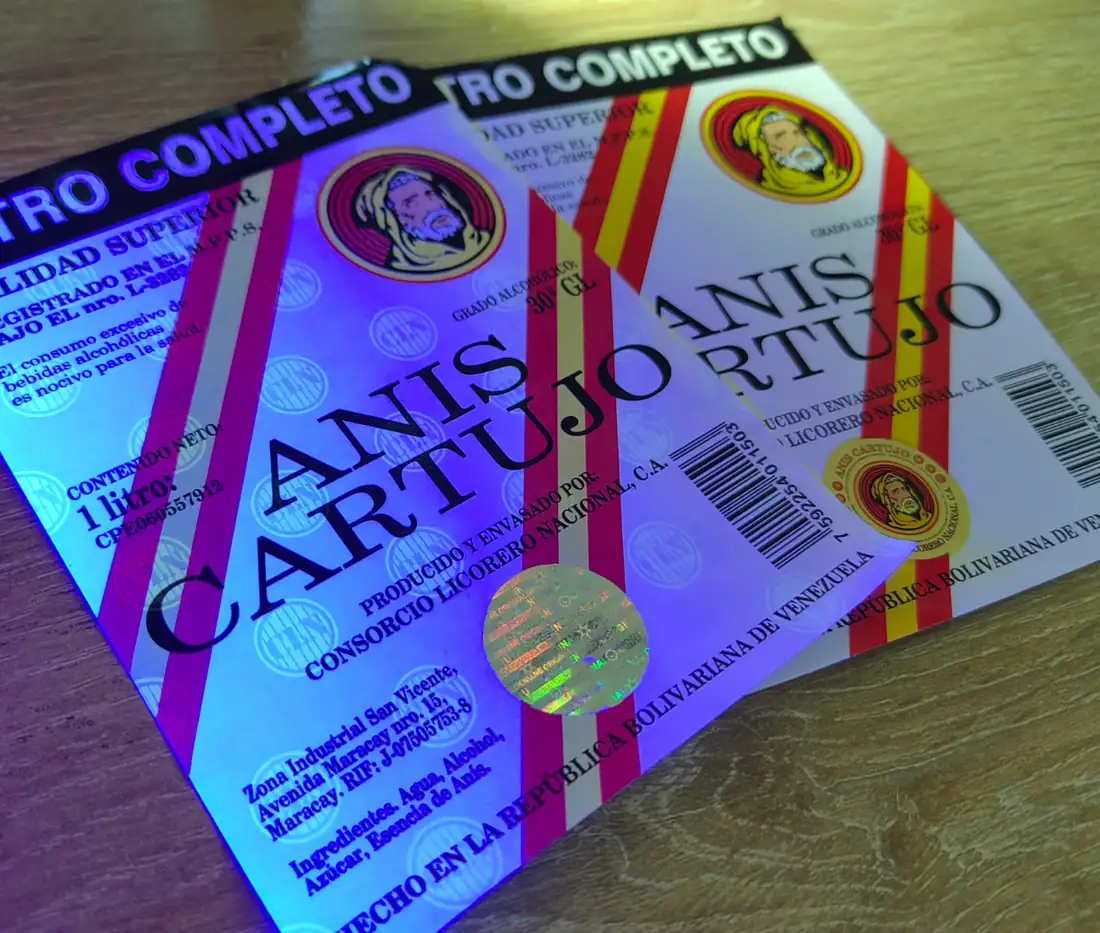 Etiquetas de licor con holograma de seguridad estampado: bajo luz UV se revela la tinta de seguridad, junto a la misma etiqueta con luz normal